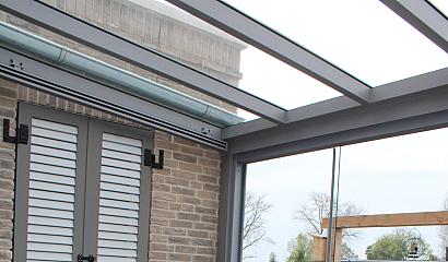 Aluminium tuinkamer aan huis met glazen dak en glazen schuifwand
